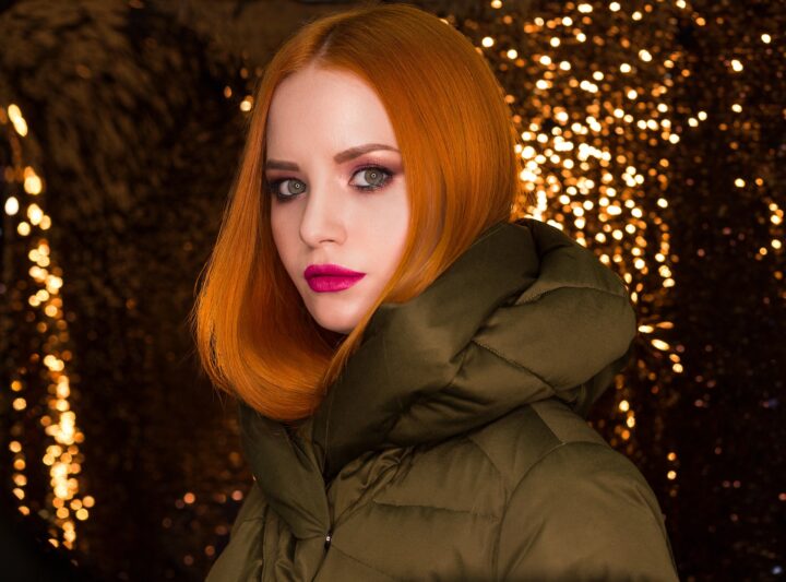 Auburn hair for spring with stunning contrasting lipstick in a cozy anorak with hood