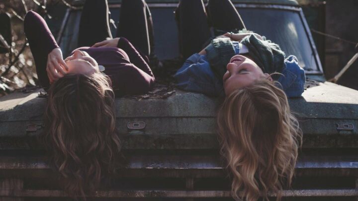 Two women with long hair lying on rusted truck
