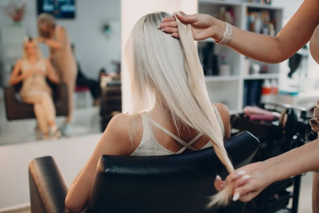 Woman with blonde hair in salon choosing hair extensions